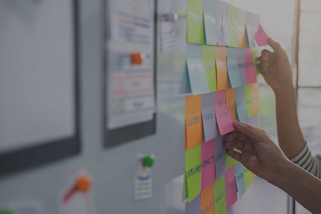 Fotografía de una pared con notas adhesivas y hojas de horarios siendo consultados