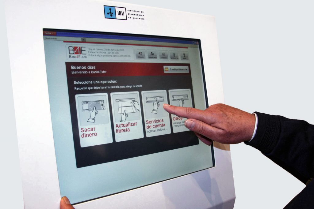 Fotografía de pantalla táctil con diferentes servicios bancarios y la mano de un hombre usánolos