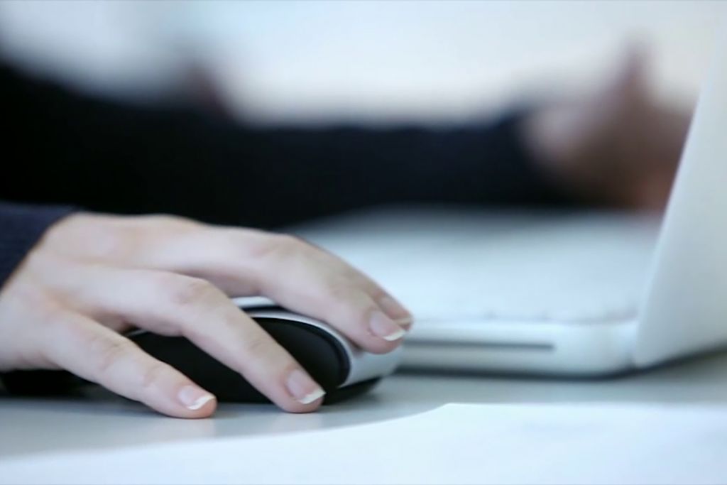 Fotografía de una mano usando el ratón de un ordenador