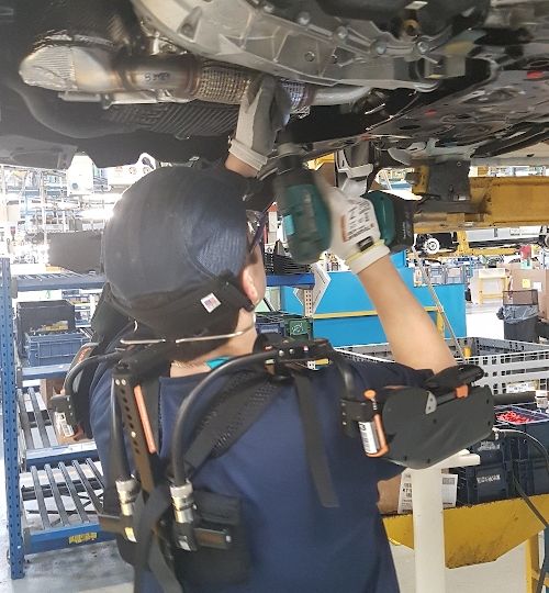 Fotografía de mecánico de coches trabajando usando un exoesqueleto