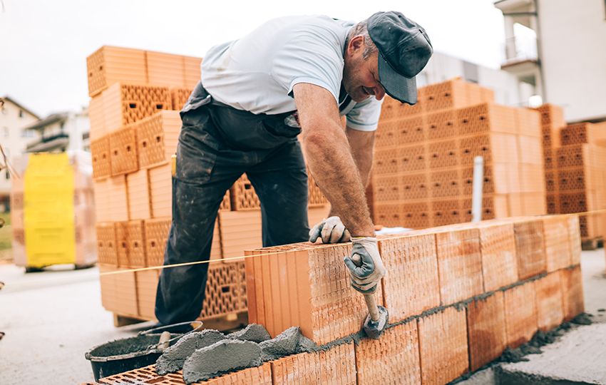 industrial worker building exterior walls, using hammer for layi