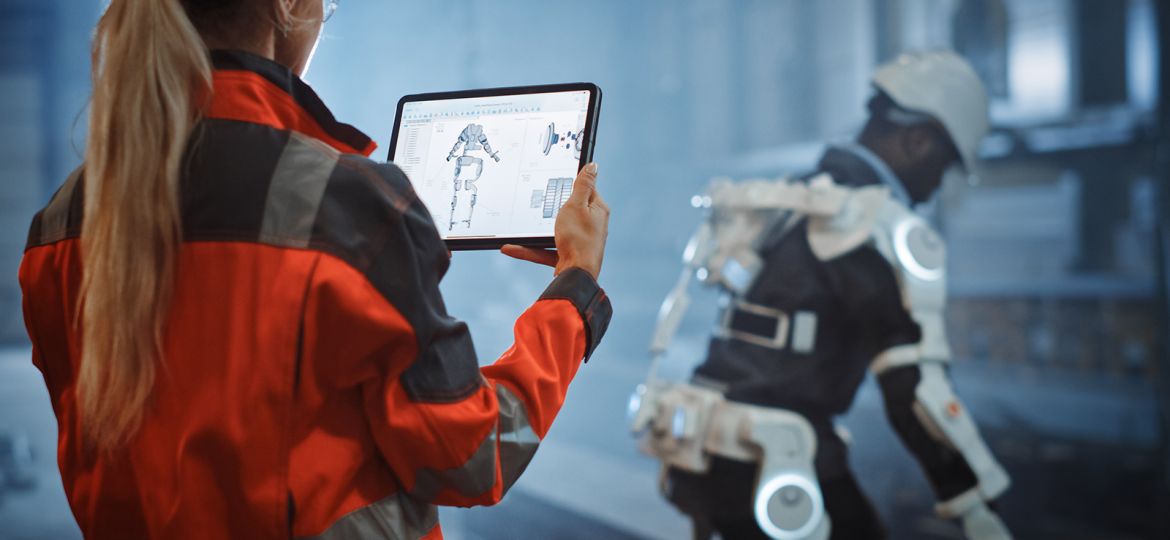 Fotografía de mujer ingeniera probando con tablet un exoesqueleto biónico