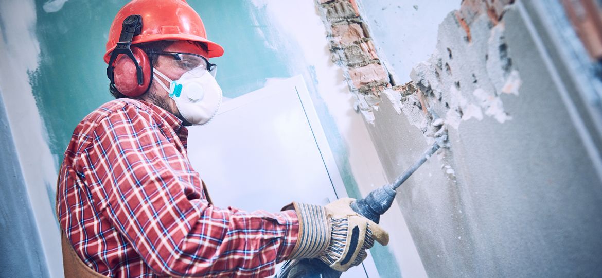 Fotografía de un albañil trabajando demoliendo un muro